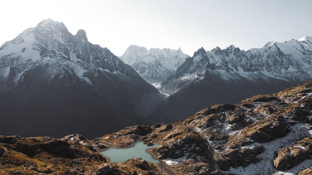Stunning view of a snow-covered mountain range with a small alpine lake in foreground.