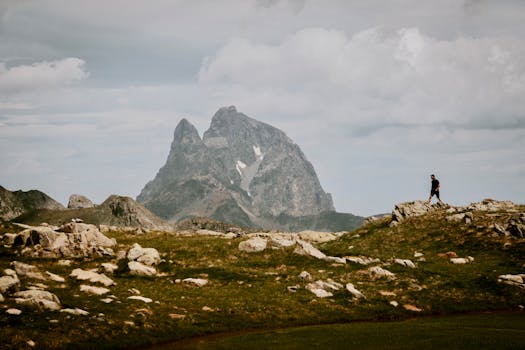 Man hiking in scenic mountain terrain with majestic Pic du Midi d'Ossau in background.