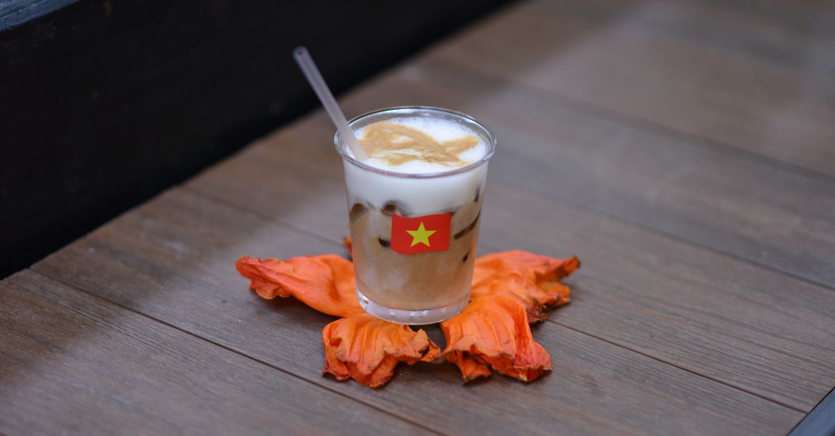 A modern Vietnamese dessert with foam and edible flowers, served in a glass jar, neon signs in background