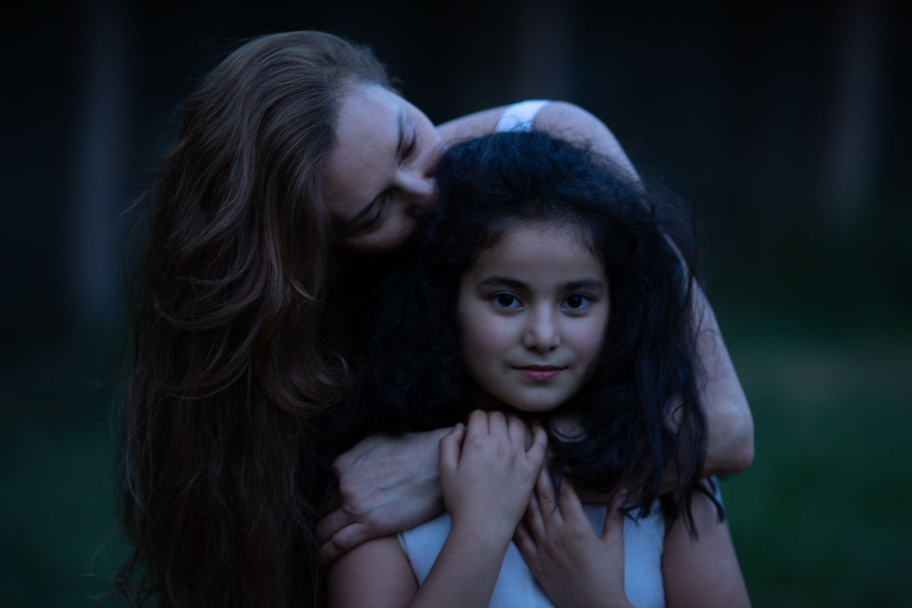 A warm embrace between a mother and her young daughter in an outdoor setting.