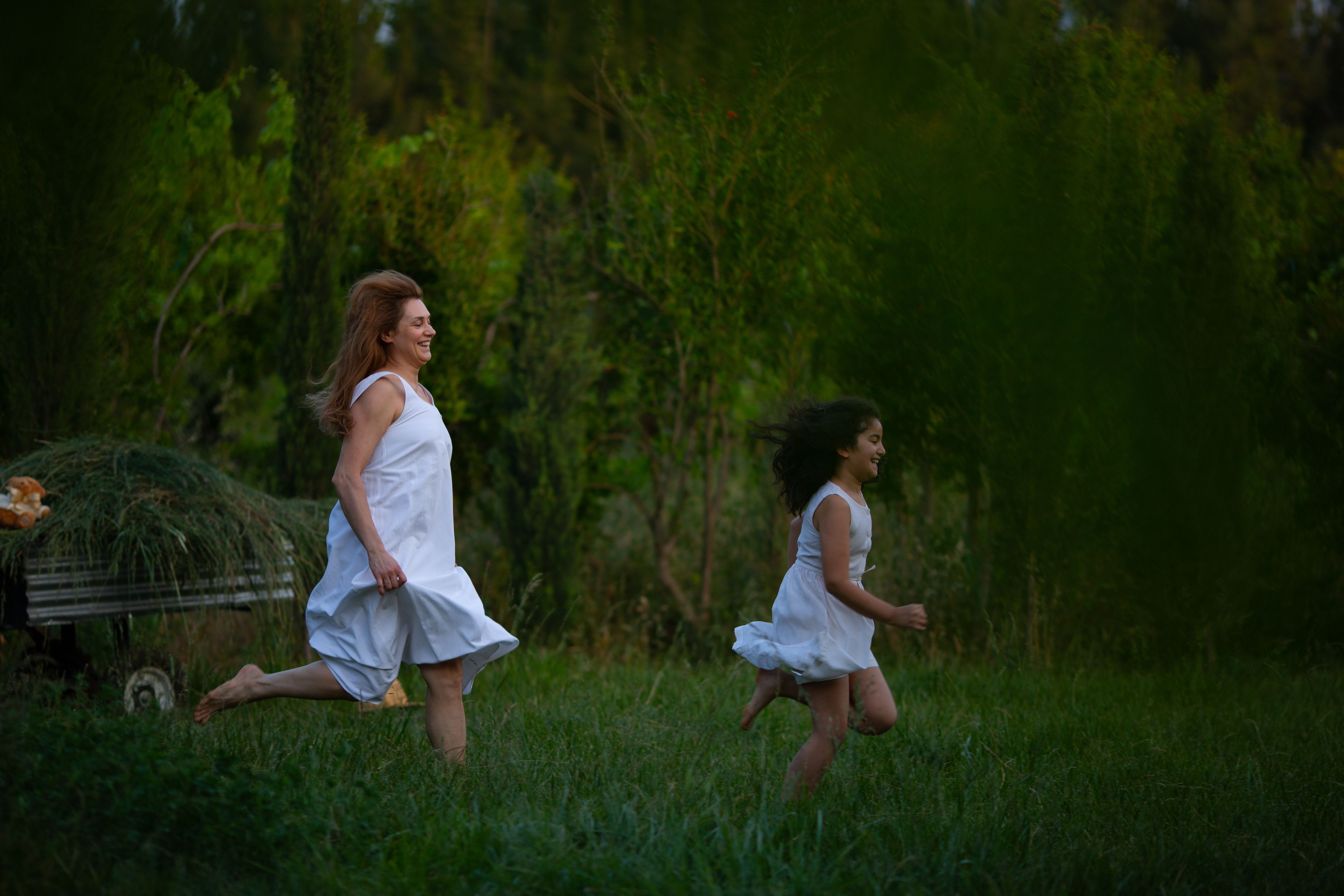 A joyful mother and daughter run through a lush green field, portraying a sense of freedom and happiness.