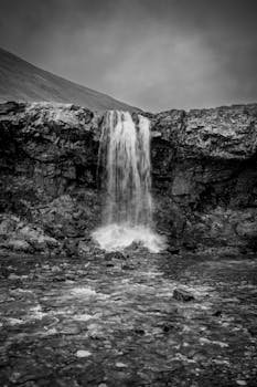 Stunning black and white photograph of a picturesque waterfall cascading over rocky cliffs in Iceland.