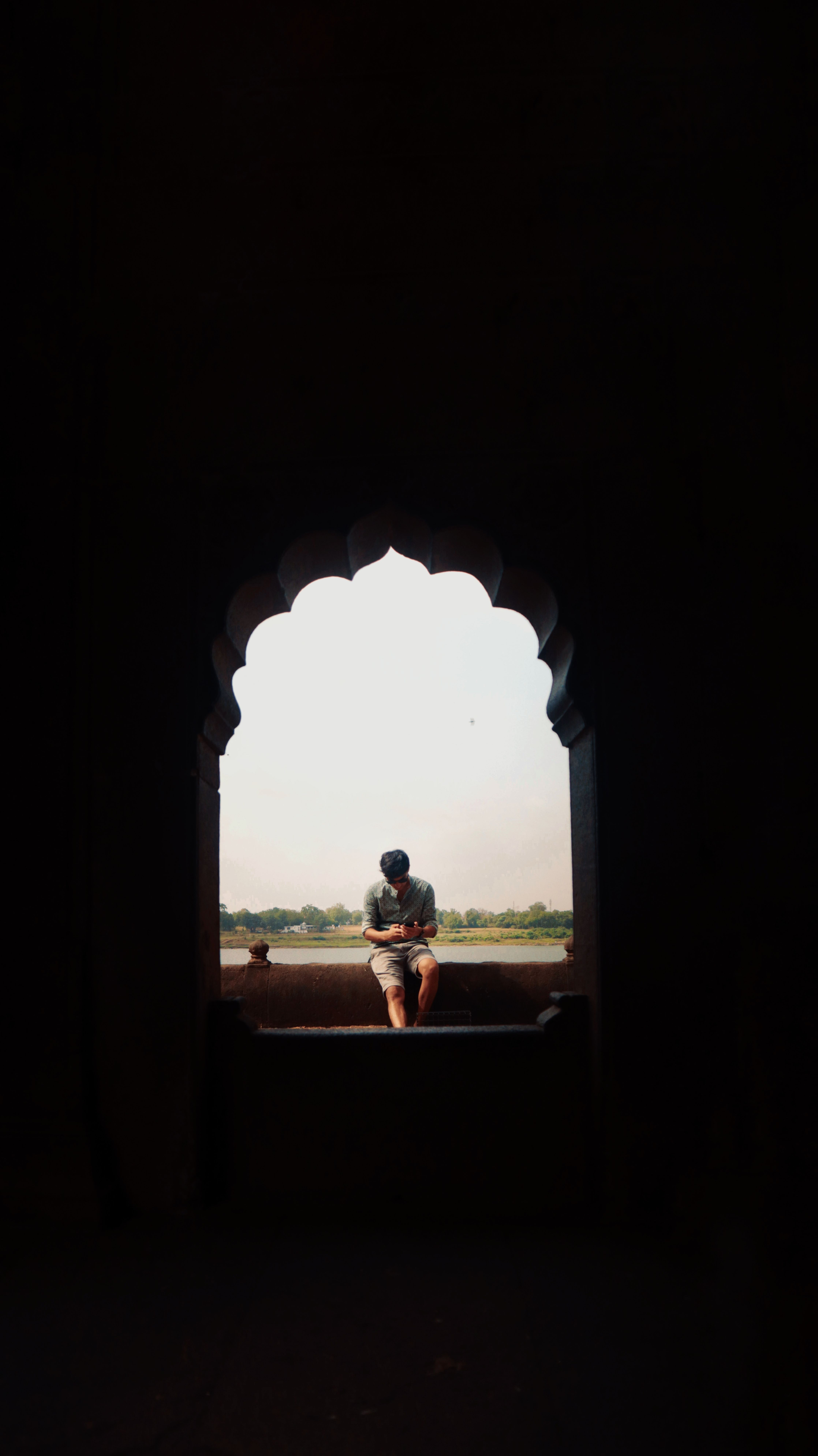 A solitary figure reads by an arched window, capturing peacefulness and solitude.