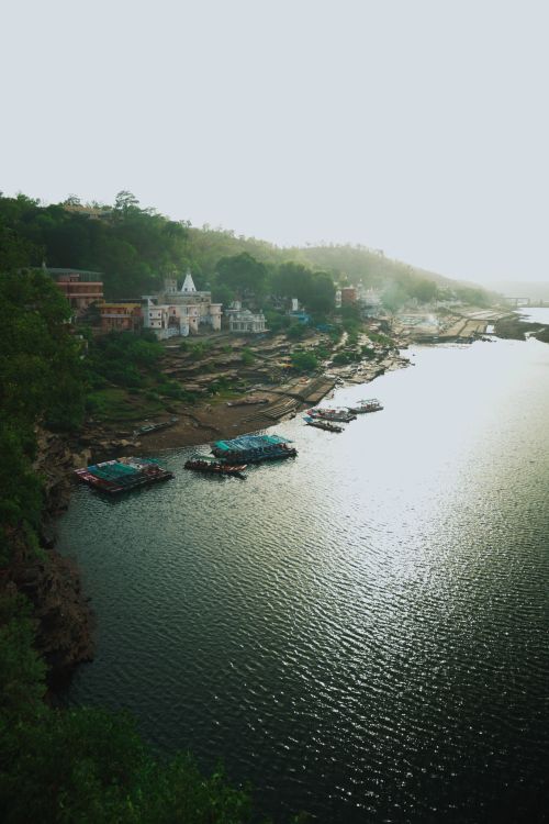 Free Serene riverside landscape of an Indian village with boats and lush greenery. Stock Photo