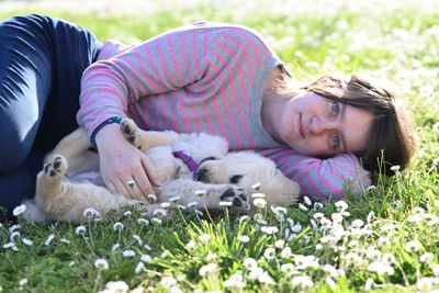 Person playing with a golden retriever puppy on a grassy lawn