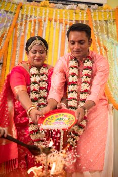 A couple partakes in a traditional Indian wedding ritual in colorful attire, showcasing cultural richness.