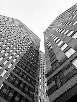 Dramatic black and white perspective of Amsterdam skyscrapers reaching towards the sky.