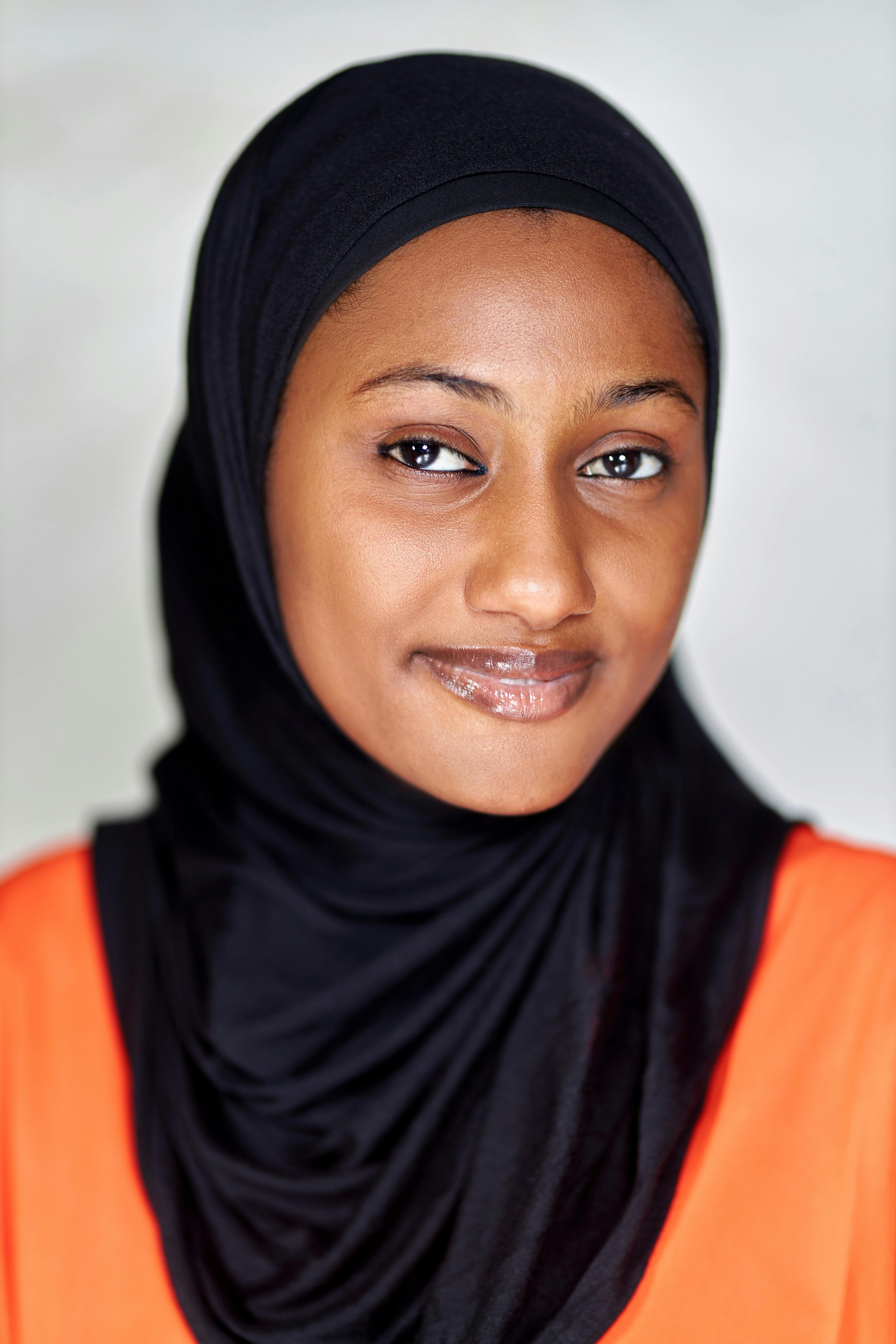 Close-up portrait of a woman wearing a hijab, exuding confidence and warmth.