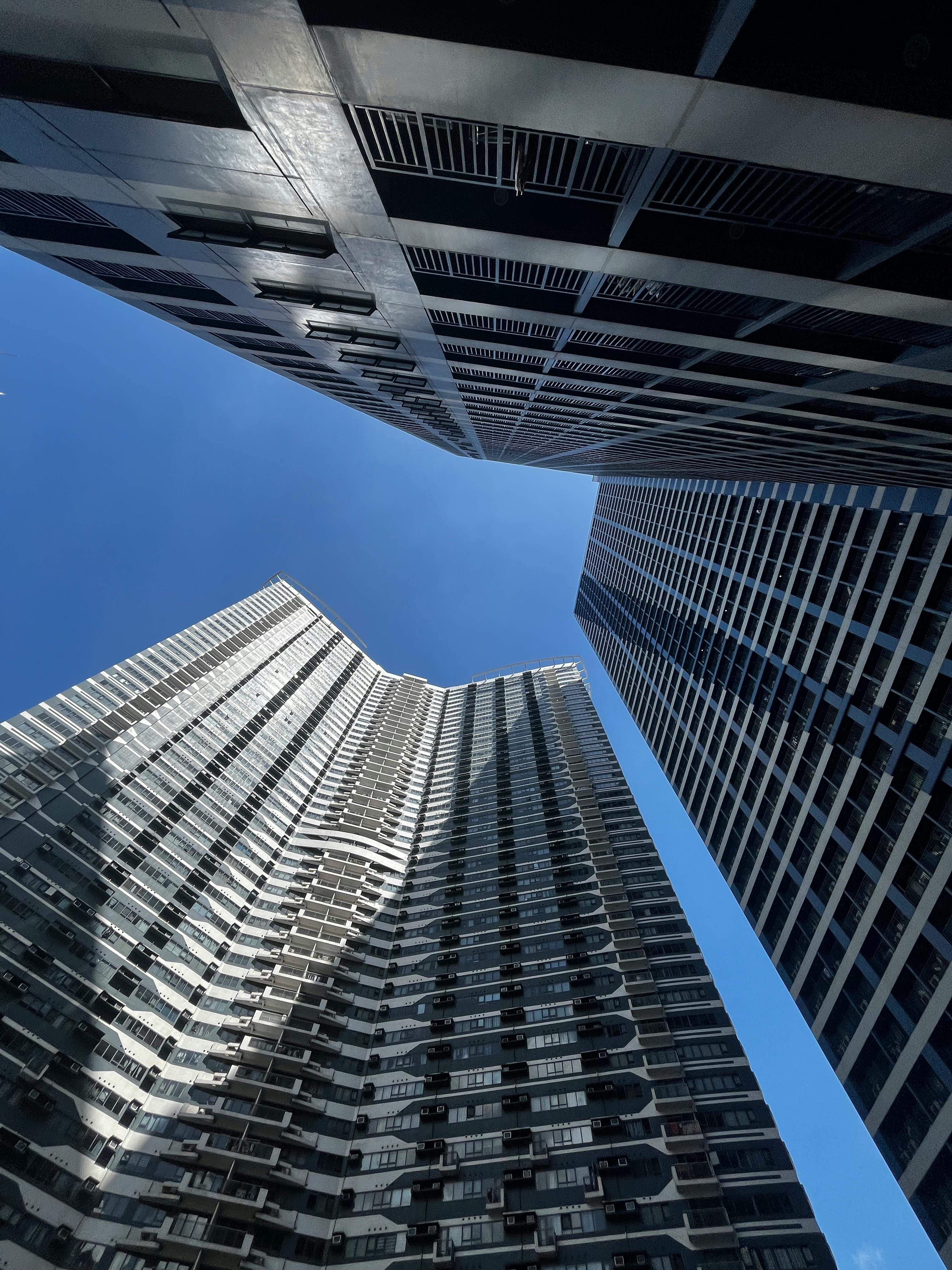 Dramatic view of modern skyscrapers against a blue sky in Makati City, Philippines.