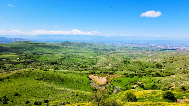 Explorez les paysages vibrants de Voghjaberd, en Arménie, avec des collines verdoyantes et des montagnes lointaines.