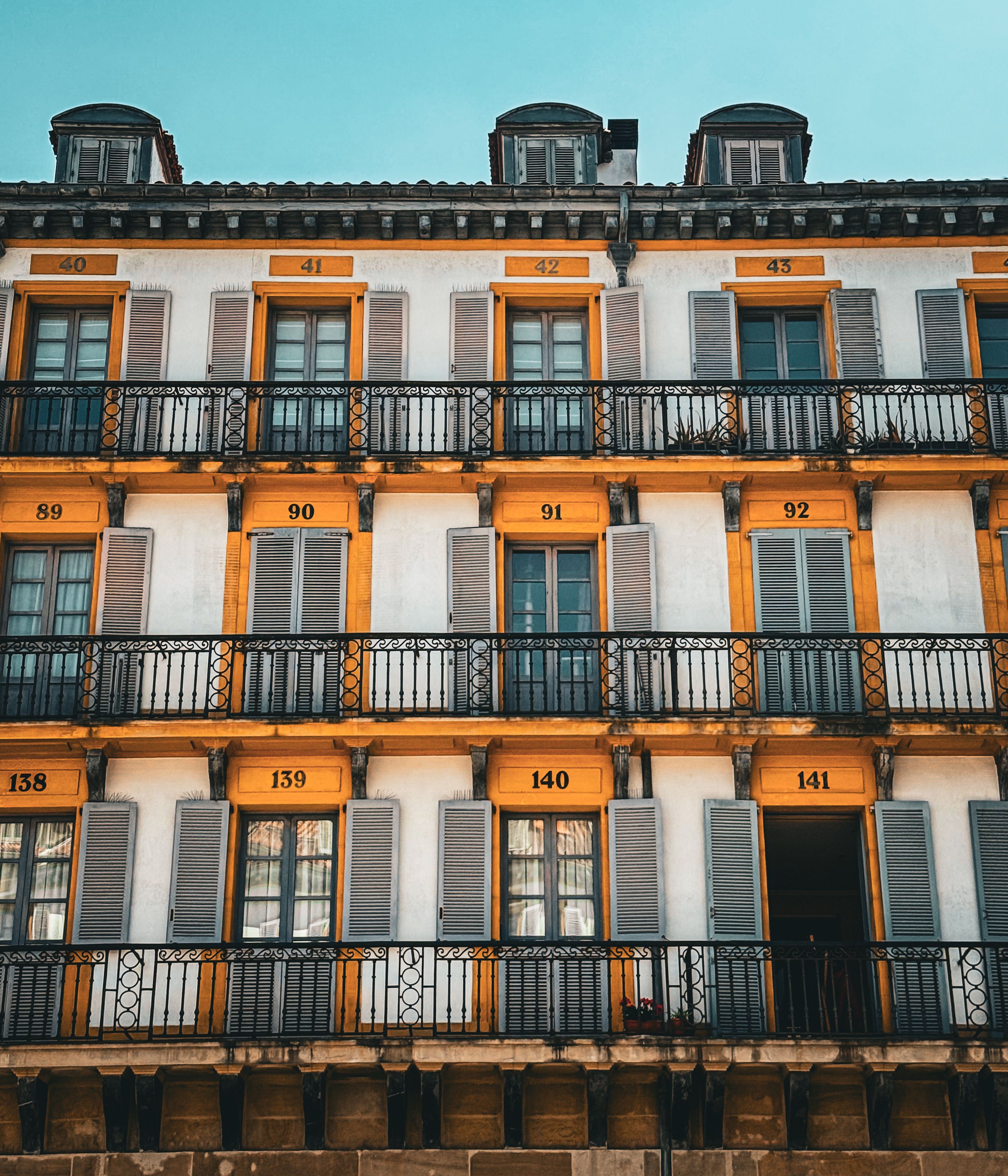 Colorful European building facade featuring numbered windows and orange frames.