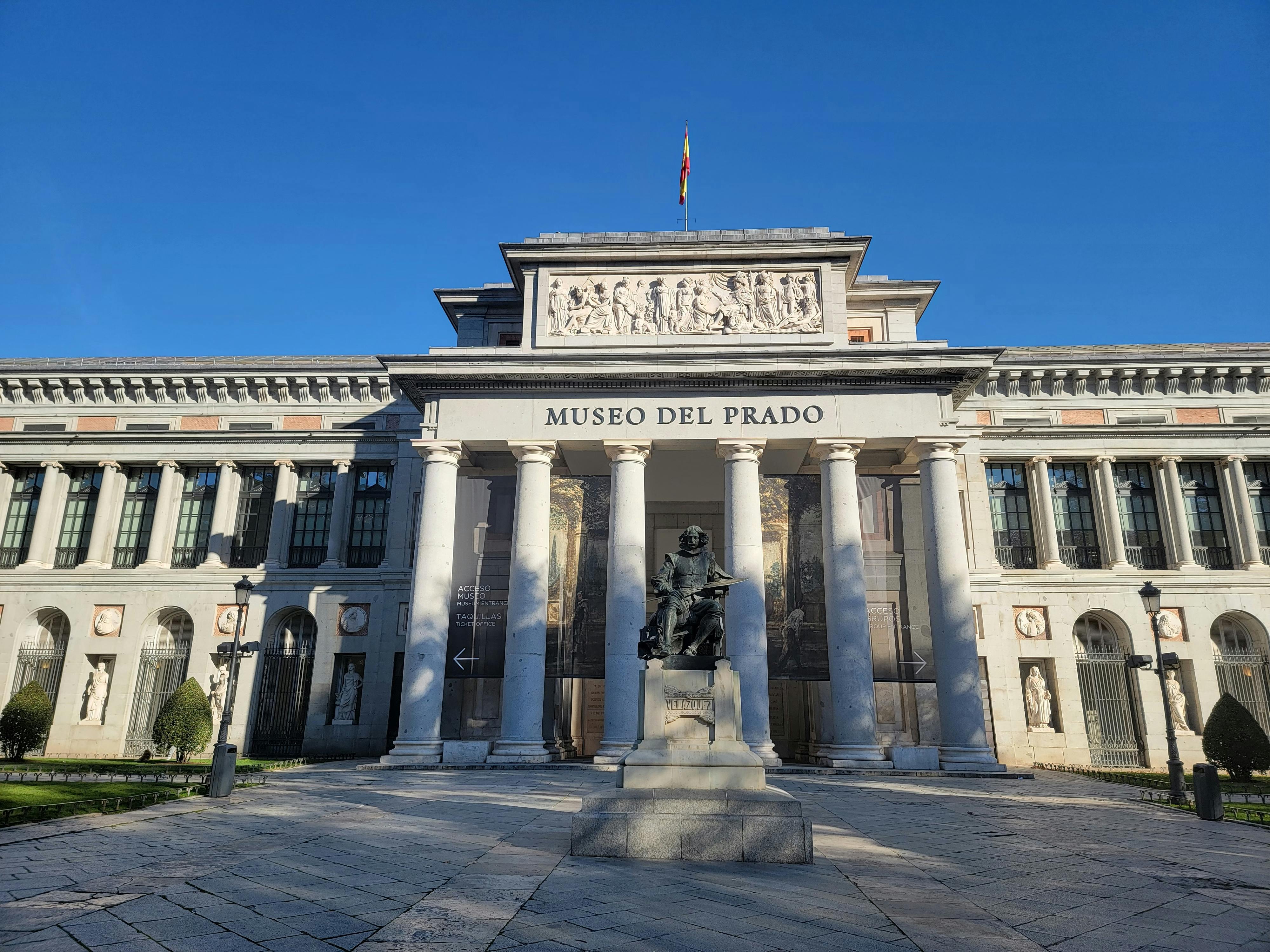 Prado Museum's iconic facade under clear blue skies in Madrid, Spain.
