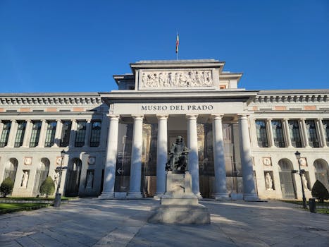Prado Museum's iconic facade under clear blue skies in Madrid, Spain.