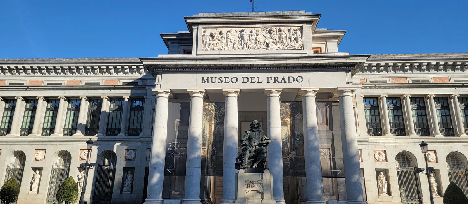 Prado Museum's iconic facade under clear blue skies in Madrid, Spain.
