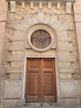 Stone facade with wooden door of Parroquia de San Ginés in Madrid, Spain, showcasing classic architecture.