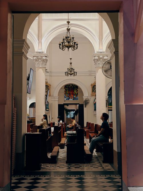 Free Peaceful interior view of a Catholic church in Ho Chi Minh City with people at prayer. Stock Photo