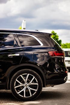 Side view of a black SUV parked outdoors under a cloudy sky, showcasing modern automotive design.