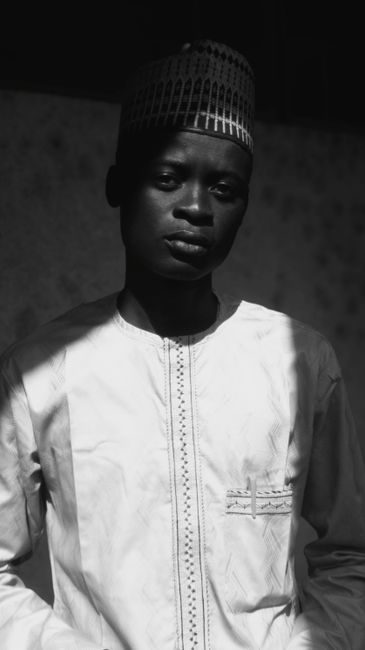 Moody black and white portrait of a man wearing traditional attire.