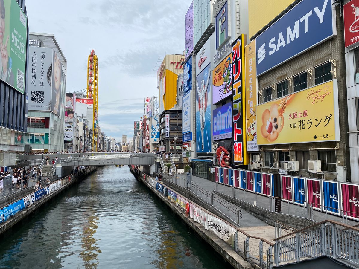 Vibrant street scene of Dotonbori Canal with colorful signs and busy pedestrians in Osaka
