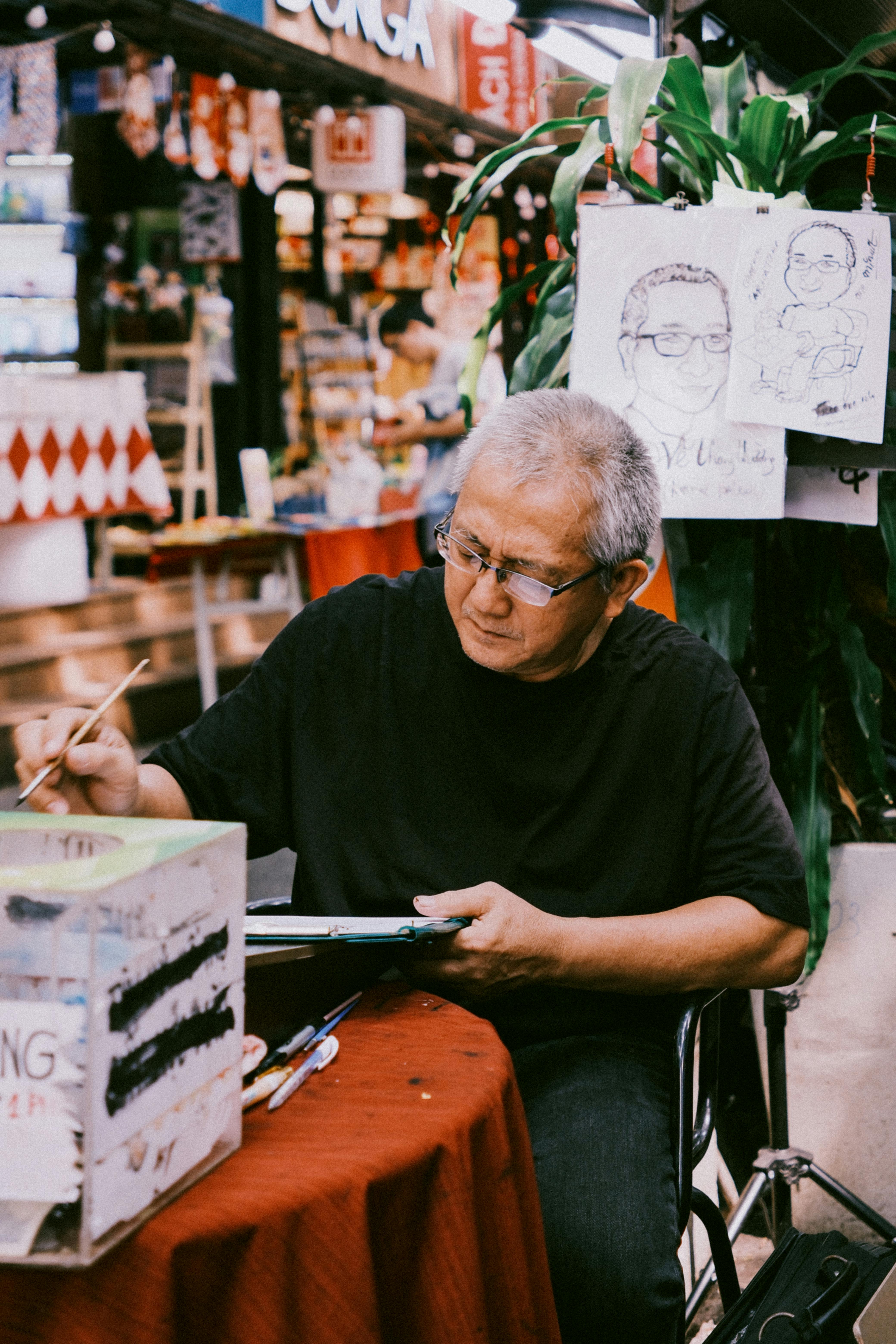 An elderly artist sketching portraits at a vibrant street market, capturing lively expressions.