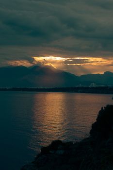 A striking sunset illuminating mountains and sea, creating a serene yet dramatic atmosphere.