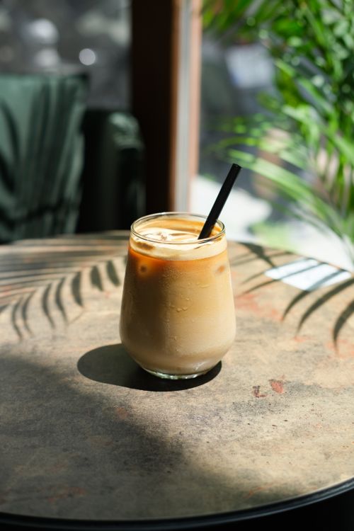 Free Chilled iced coffee with a straw in sunlit Istanbul cafe, tropical ambiance. Stock Photo