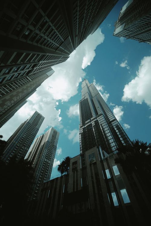 Free Dynamic view of towering skyscrapers against a vibrant blue sky with scattered clouds. Stock Photo