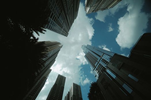 Dynamic view of skyscrapers stretching into a vibrant blue sky dotted with clouds.