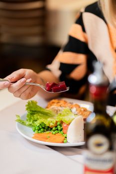 A close-up of a healthy meal featuring fresh vegetables, grilled chicken, and a fork with beetroot.