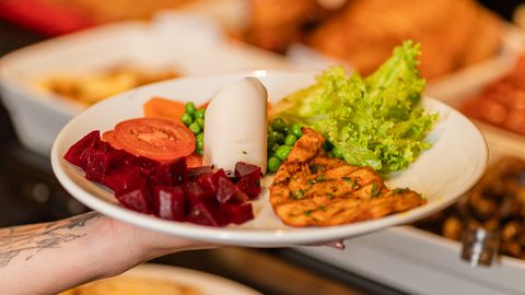 A visually appealing gourmet salad with grilled chicken and fresh vegetables on a white plate.