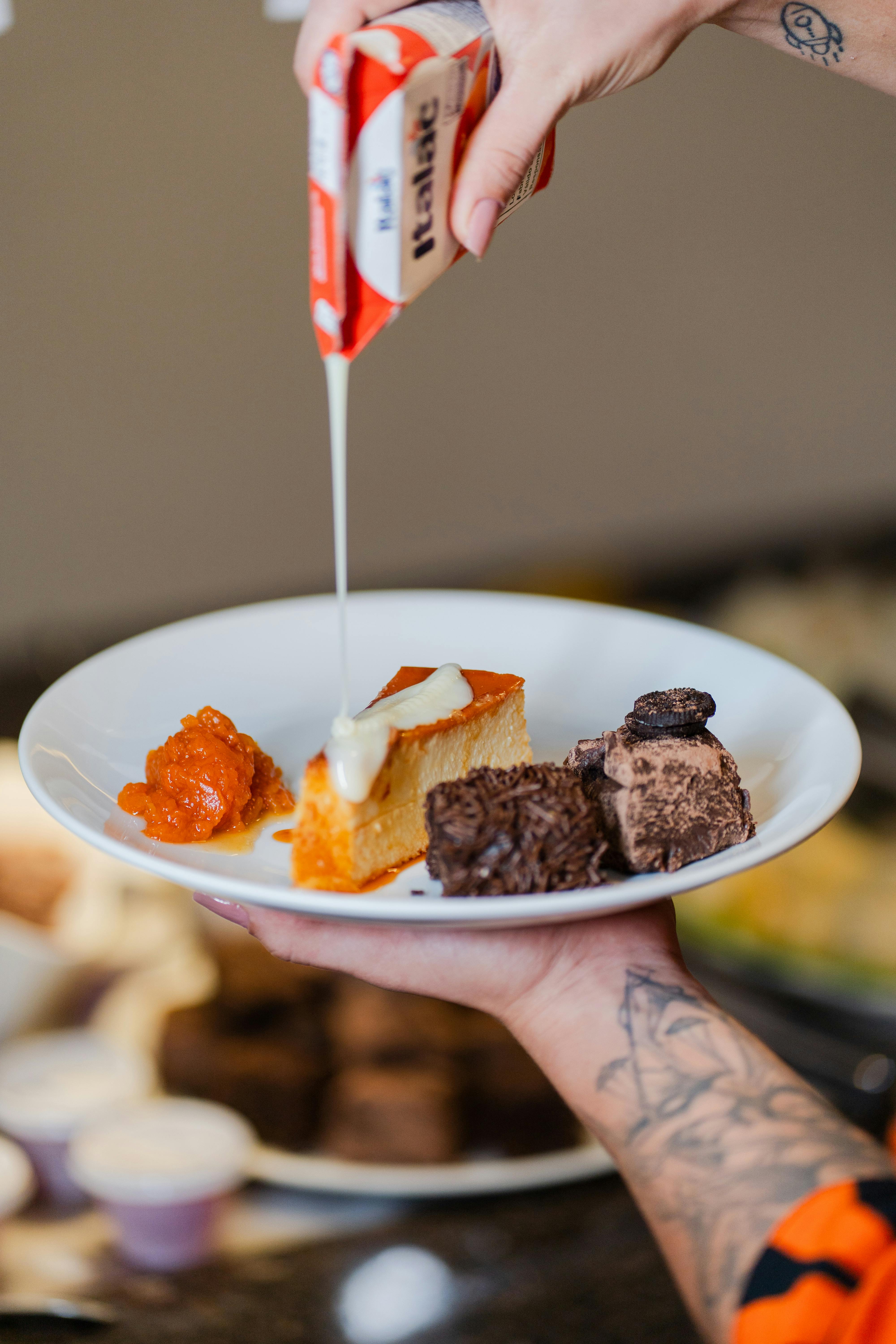 Close-up of syrup being drizzled on a dessert plate with various sweet treats.
