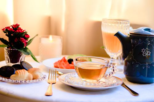 Free A warm and inviting tea setting with biscuits, candlelight, and fresh flowers. Stock Photo