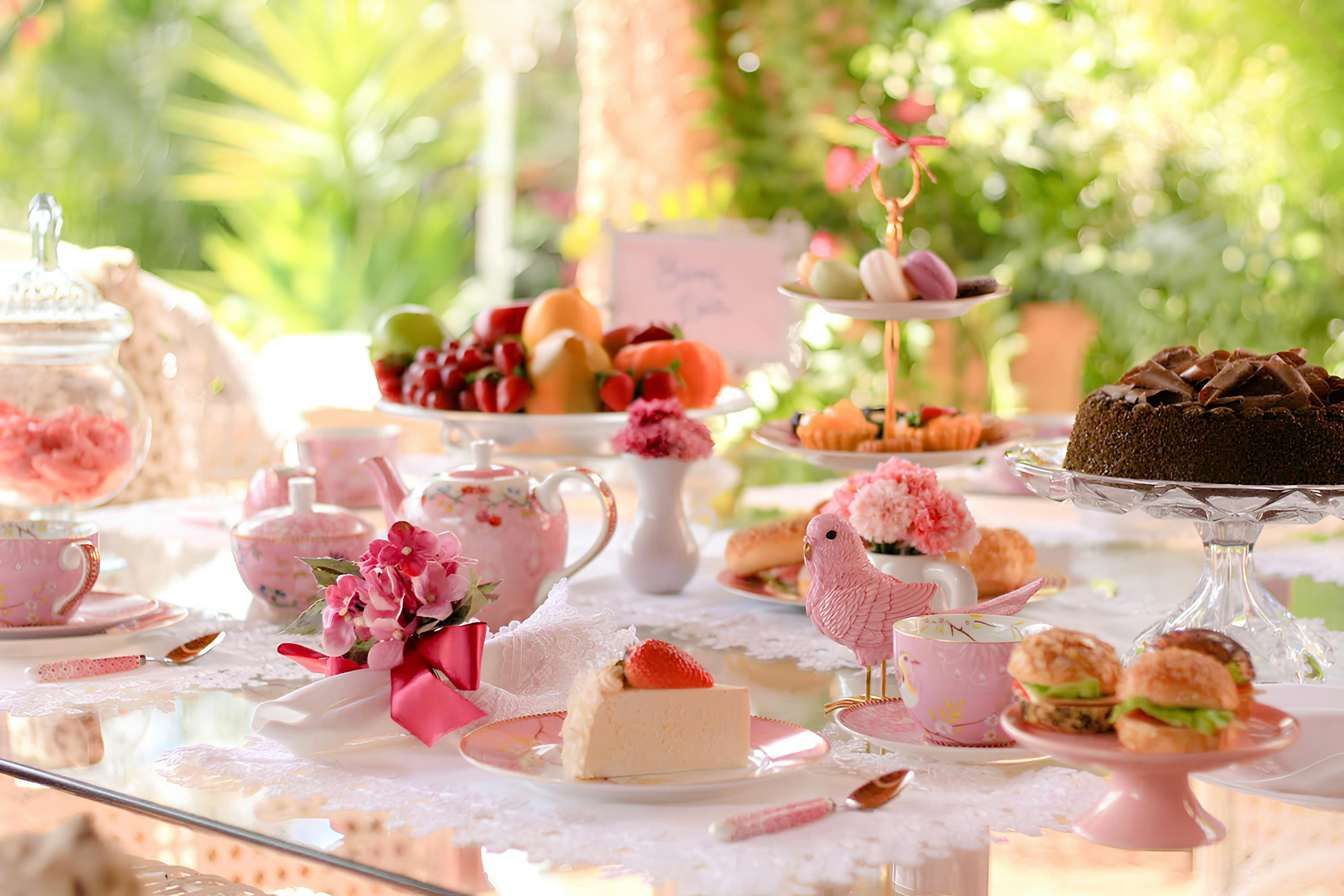 Charming outdoor tea setup with cakes, sweets, and floral decor, perfect for a spring gathering.