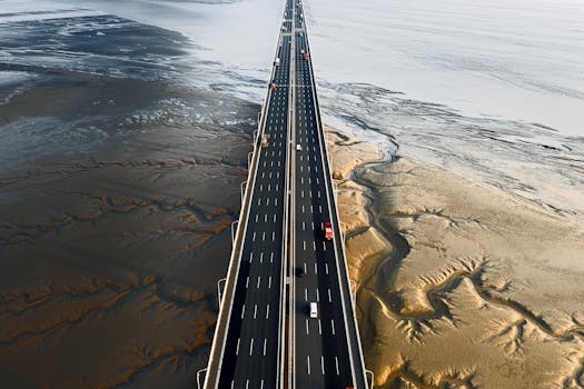 A stunning aerial shot of a coastal highway stretching across expansive mudflats under clear skies.