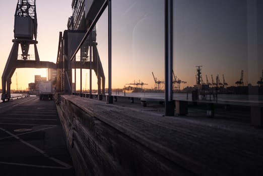 Stunning sunset view at Hamburg harbor with cranes reflected in glass facade.