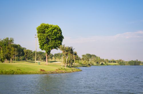 Free Beautiful view of a green golf course and lake under a bright blue sky, evoking tranquility and leisure. Stock Photo