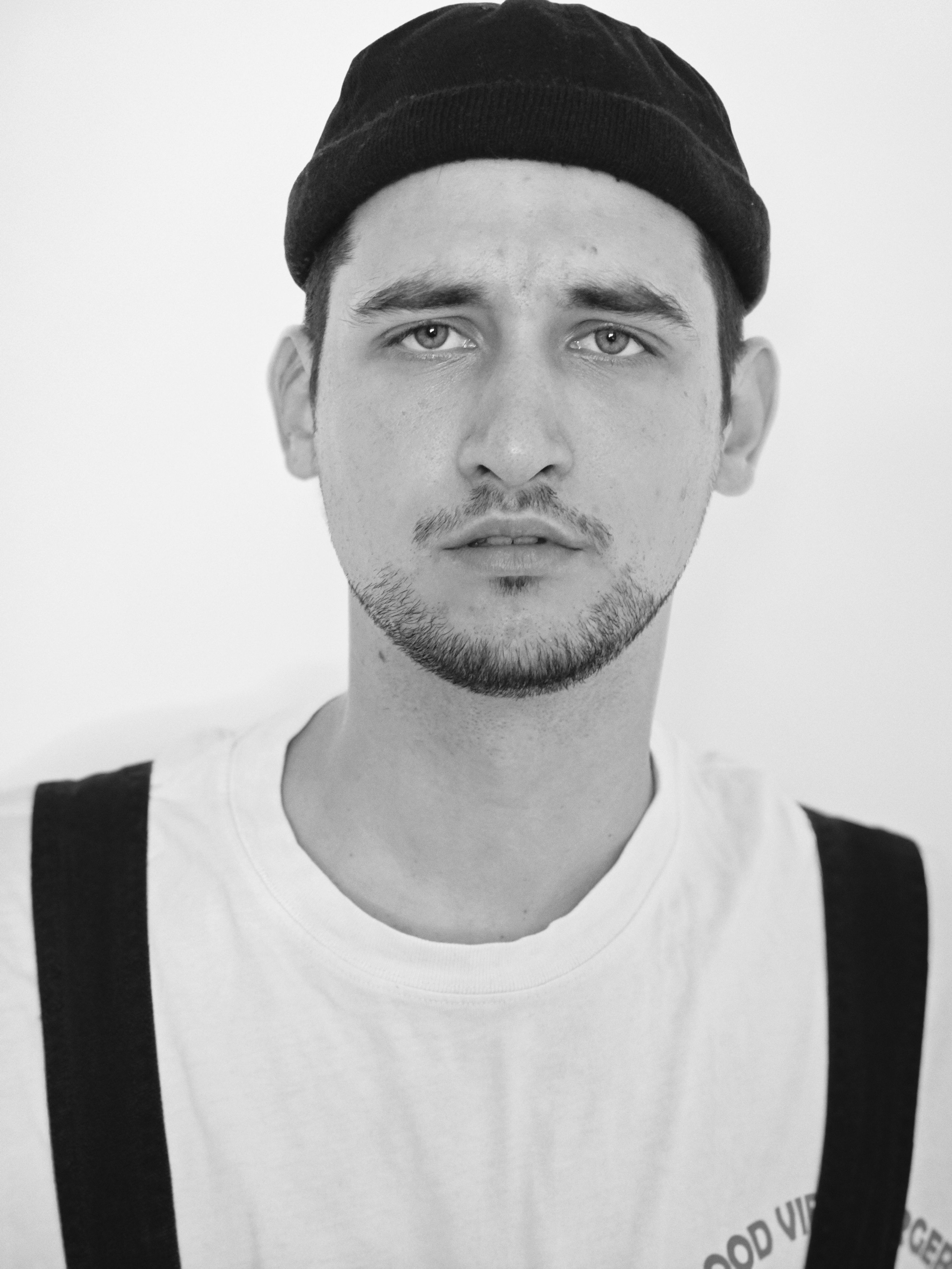 Black and white portrait of a young man wearing a cap and white shirt.