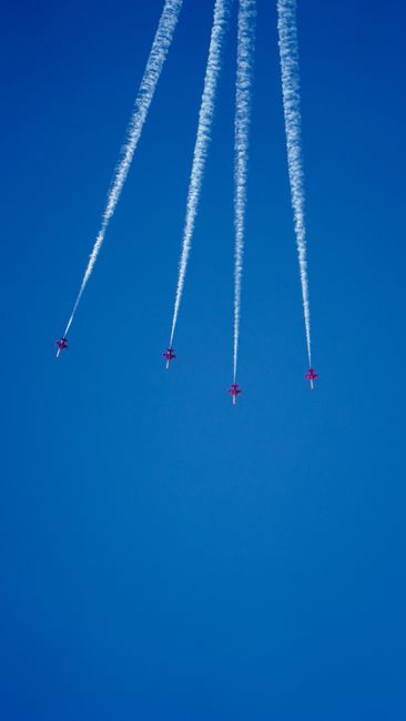 Fotomural Cuatro jets militares dejando estelas de humo en un hermoso cielo azul, mostrando precisión aérea.