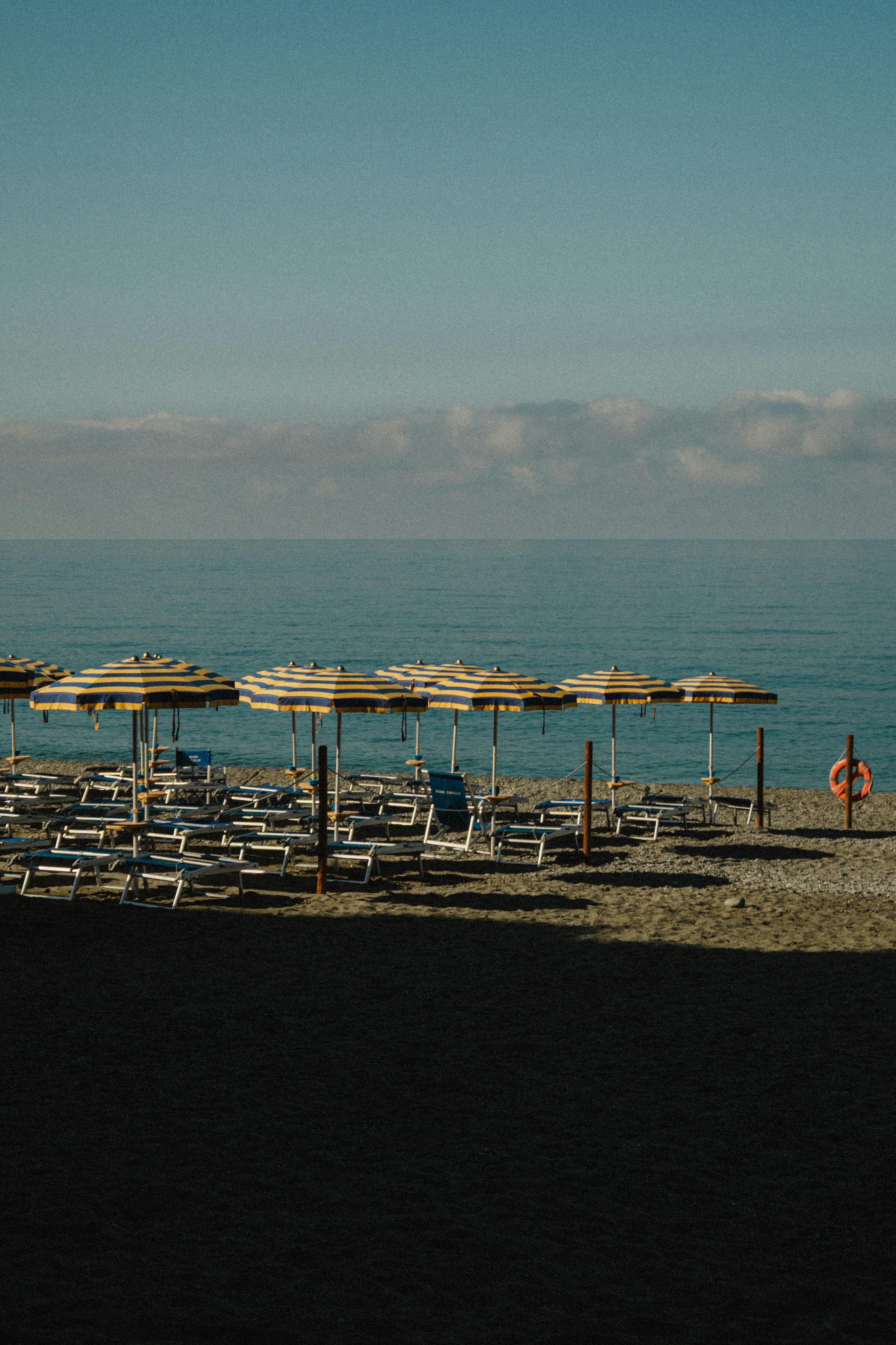 Tranquil beach scene with umbrellas and deck chairs on a sunny day by the sea.