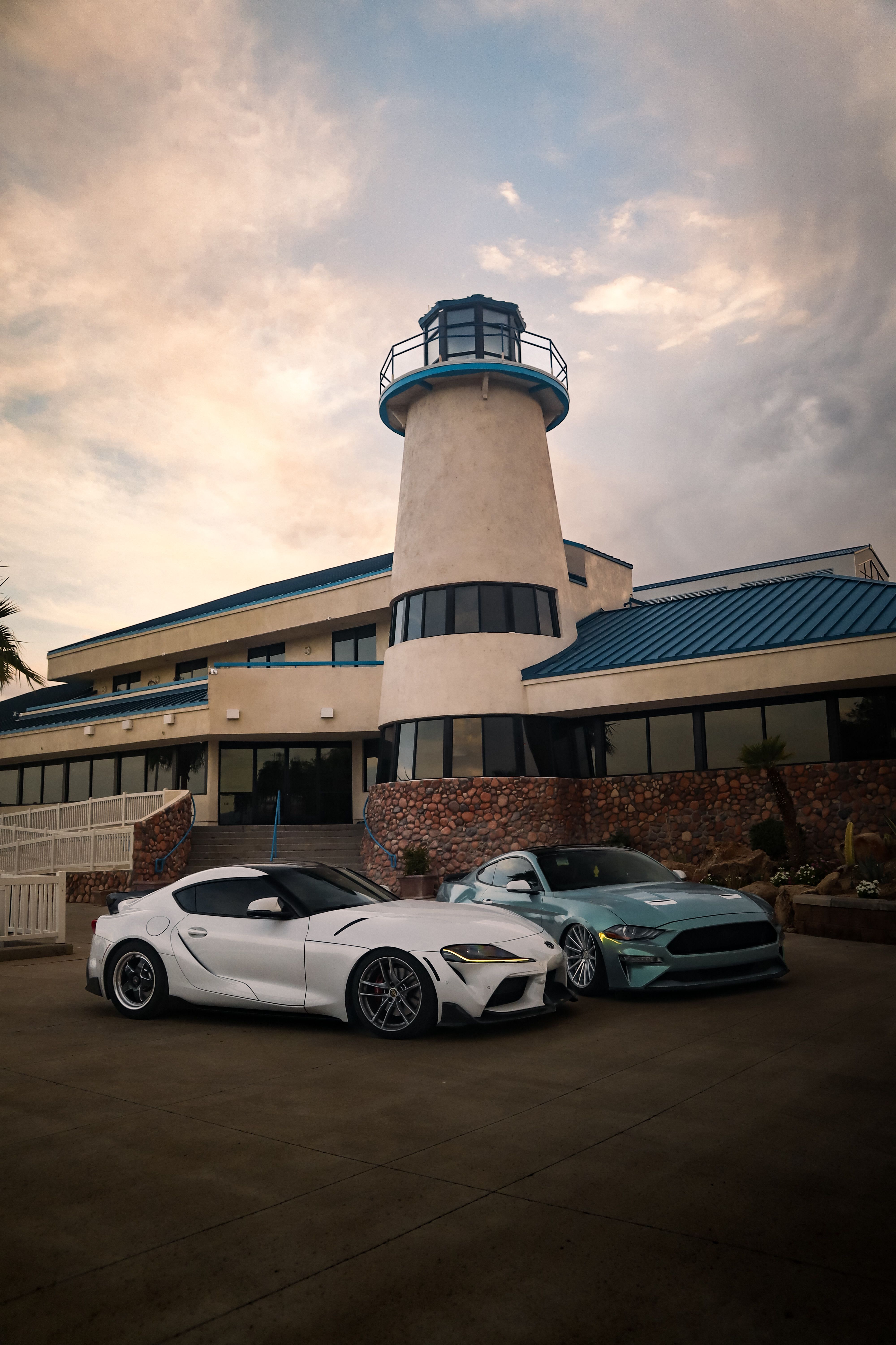 Luxury Cars Parked Near Lighthouse-Inspired Building · Free Stock Photo