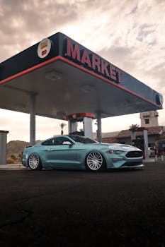 Modern car parked at a retro gas station with a cloudy sky background.