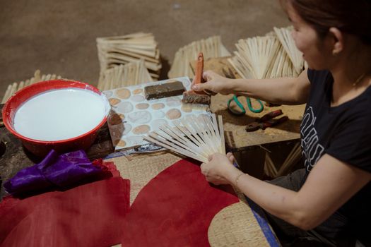 An artisan crafting traditional handmade fans using natural materials in a workshop.