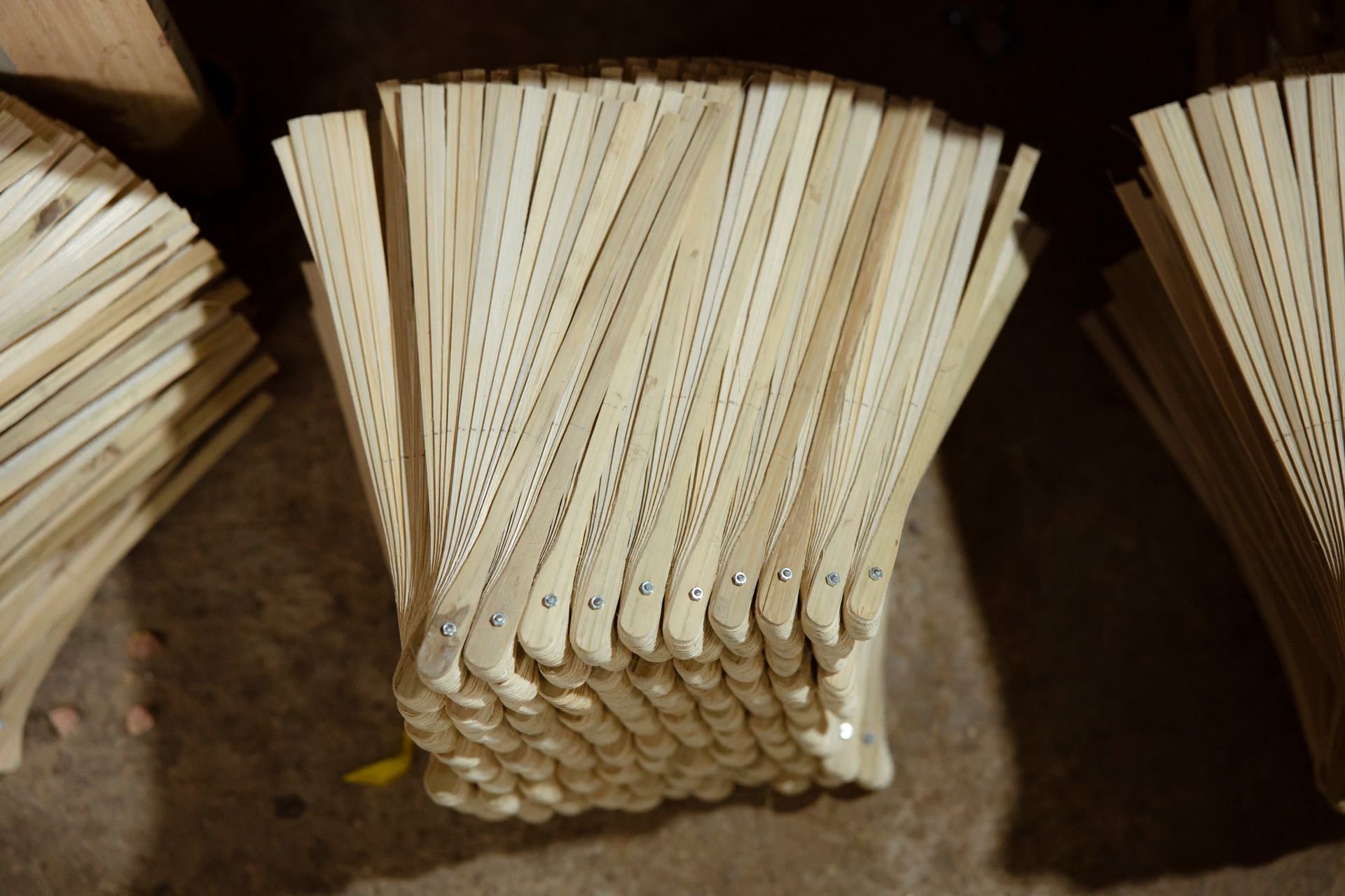 Stacks of wooden fan blades arranged in a workshop, emphasizing craftsmanship and material texture.