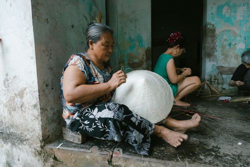 Free Elderly women skillfully crafting traditional conical hats in a rustic outdoor setting. Stock Photo