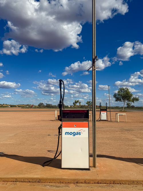 Free A solitary petrol pump stands alone in the vast Australian outback, under a vibrant blue sky. Stock Photo