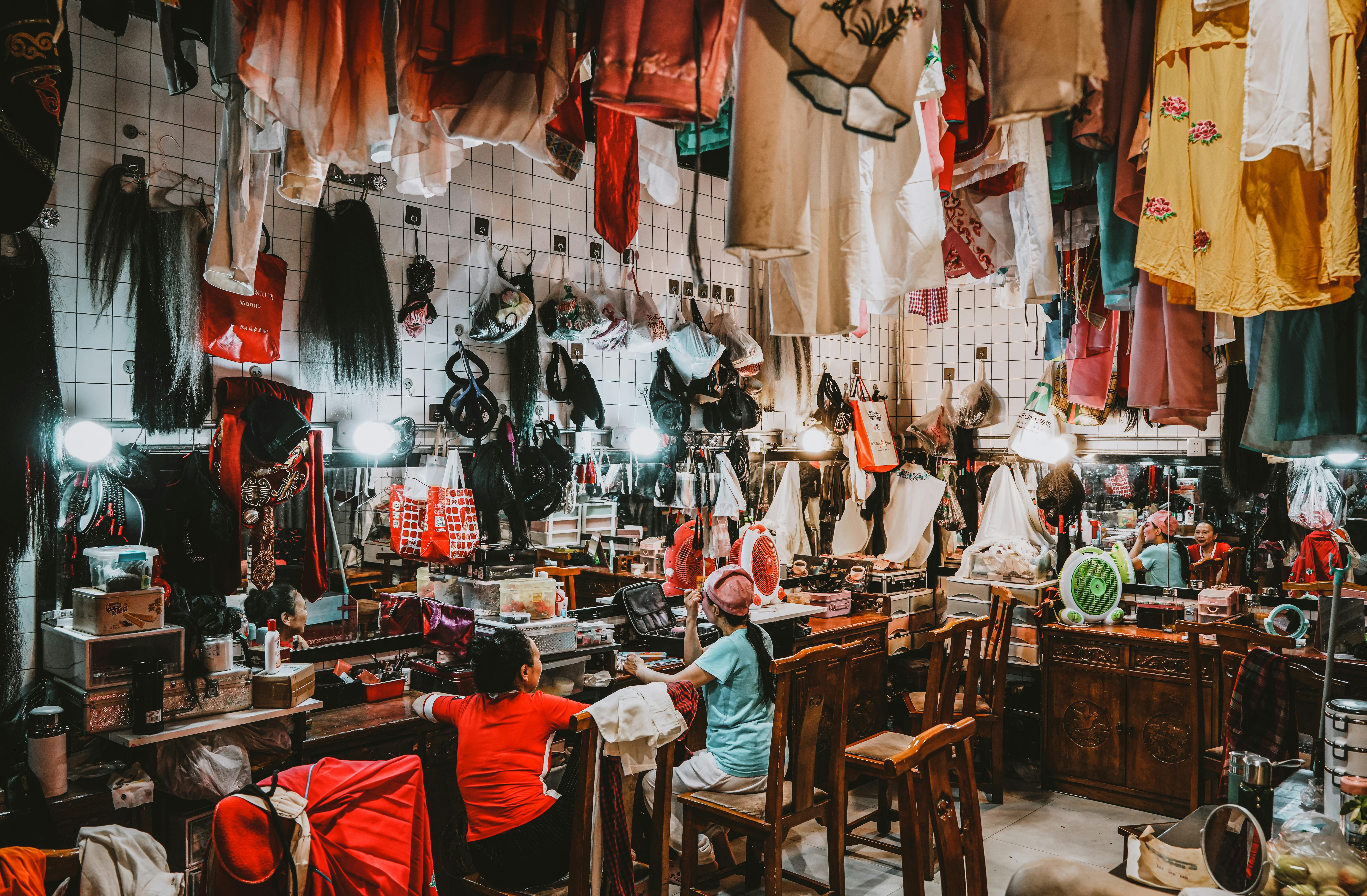 Free Busy theater dressing room filled with colorful costumes and two women preparing. Stock Photo