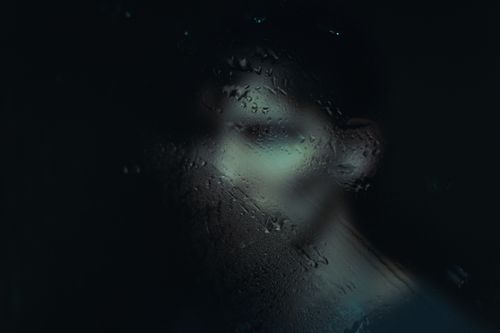 Free Ethereal silhouette behind misted glass creates a deep, mysterious atmosphere. Stock Photo