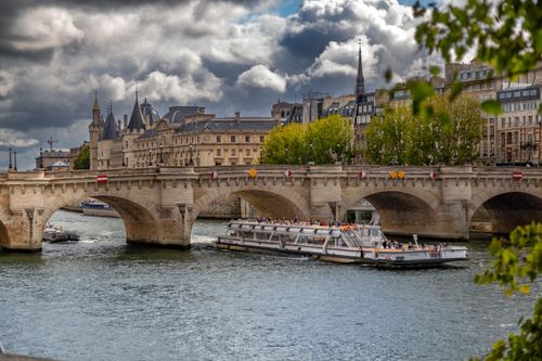 Free Scenic view of the historic Pont Neuf and a cruise boat on the Seine in Paris. Stock Photo
