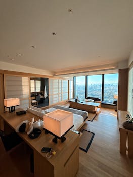 Minimalist hotel room with panoramic city view and modern decor.