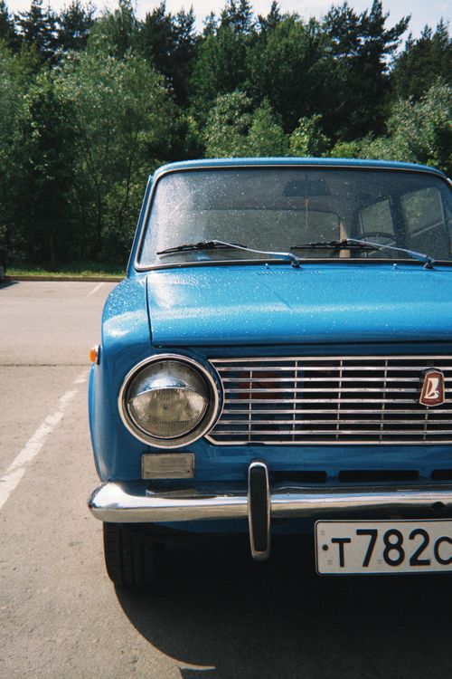 Free Classic blue vintage car parked outdoors in sunlight near forested area. Stock Photo